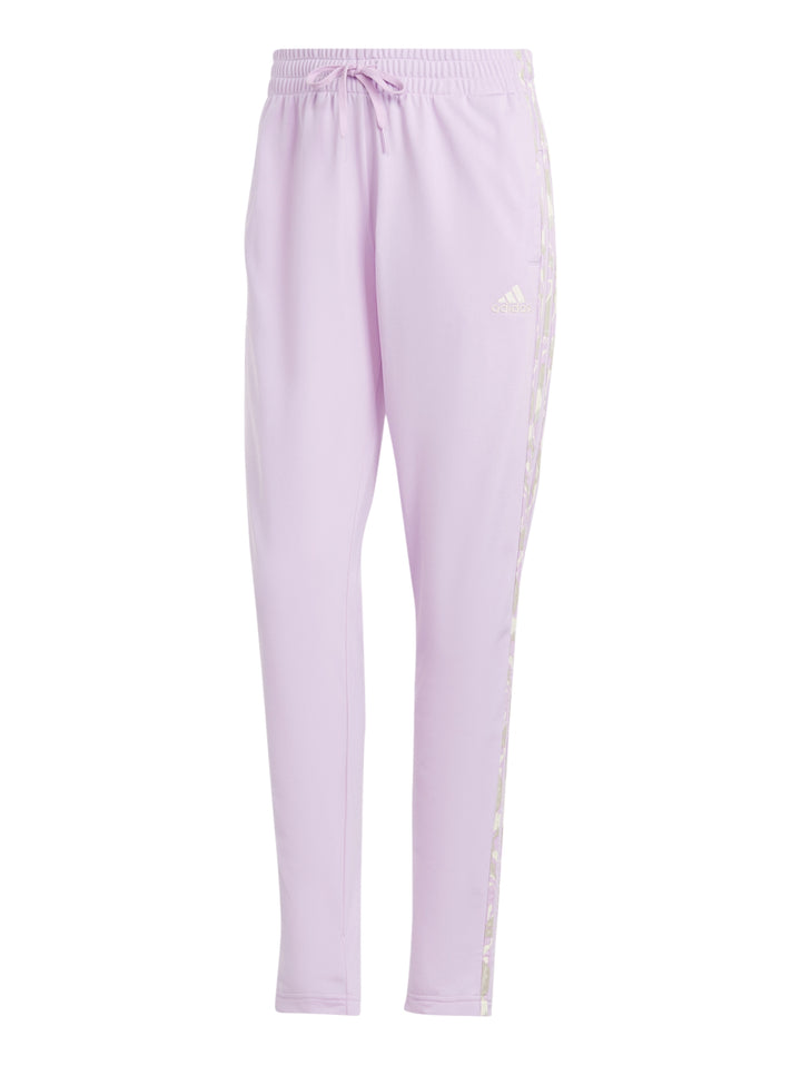 Mujer vistiendo pantalones deportivos Adidas en color lila con rayas laterales multicolores.
