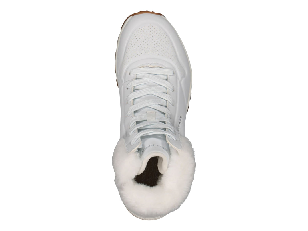 Botín deportivo Skechers blanco con forro interior de peluche blanco y suela color café.