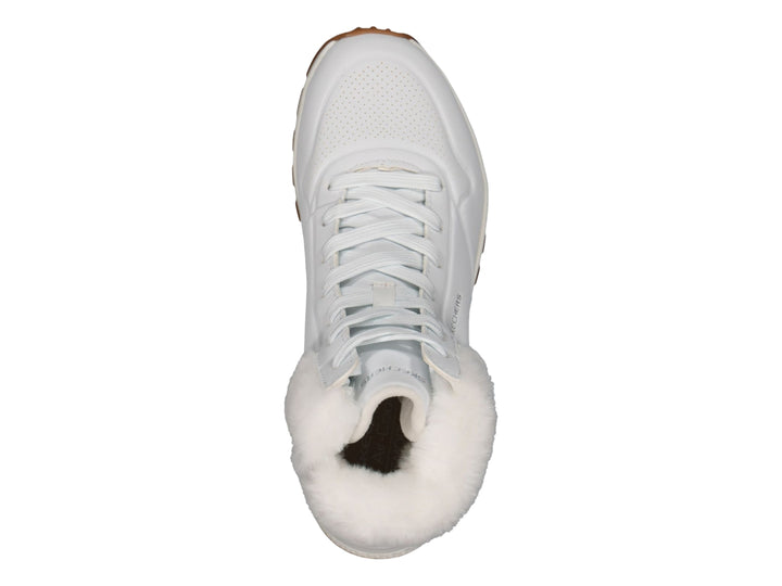 Botín deportivo Skechers blanco con forro interior de peluche blanco y suela color café.