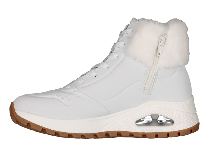 Botín deportivo Skechers blanco con forro interior de peluche blanco y suela color café.