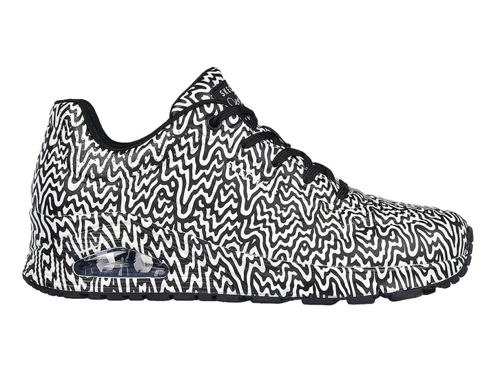 Tenis deportivos Skechers con estampado ondulado en blanco y negro y suela con amortiguación visible.