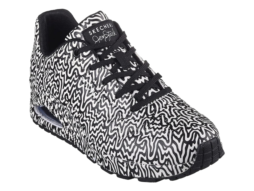 Tenis deportivos Skechers con estampado ondulado en blanco y negro y suela con amortiguación visible.