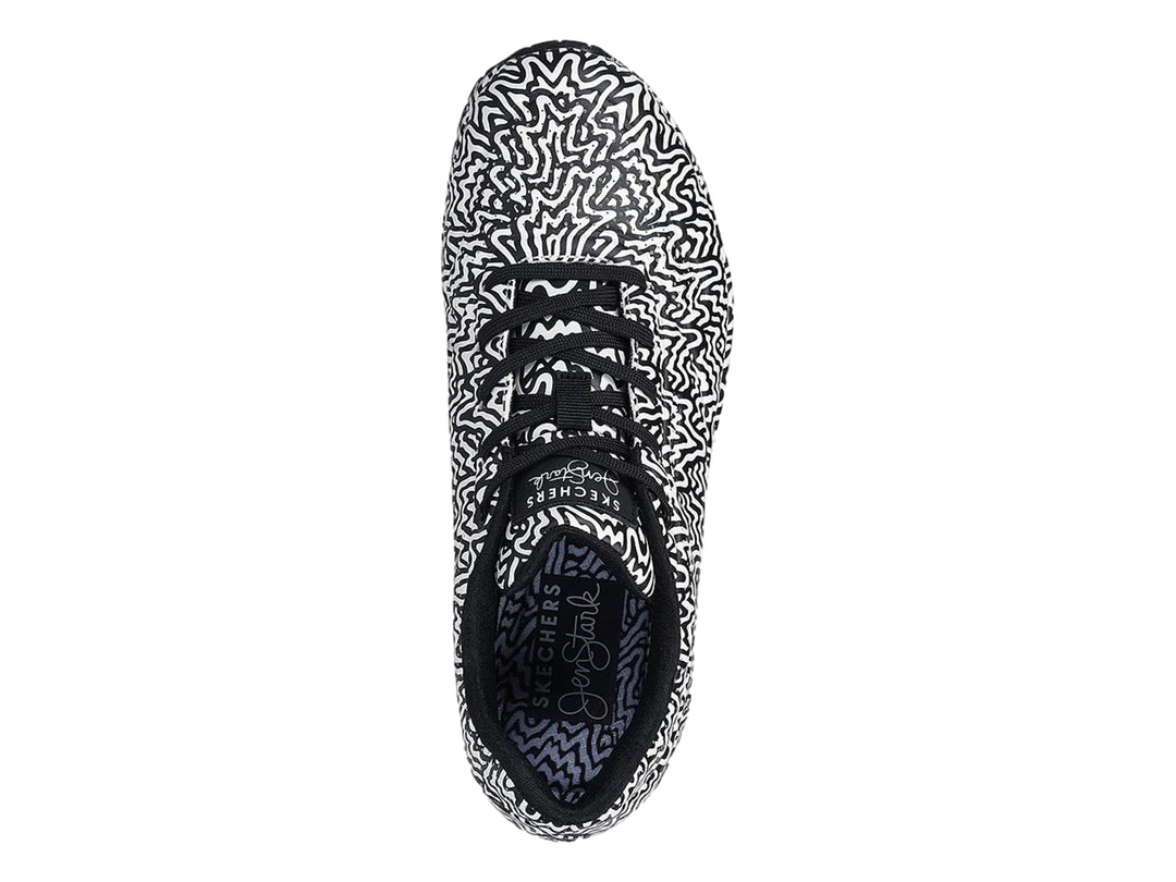 Tenis deportivos Skechers con estampado ondulado en blanco y negro y suela con amortiguación visible.