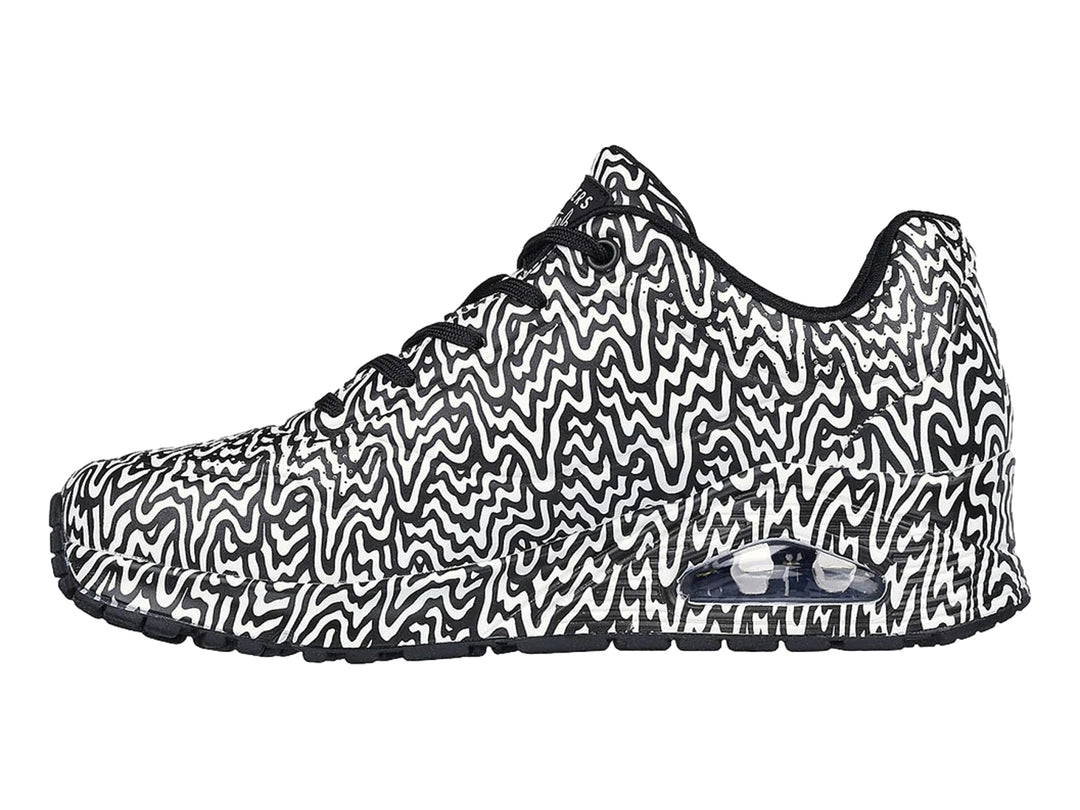 Tenis deportivos Skechers con estampado ondulado en blanco y negro y suela con amortiguación visible.