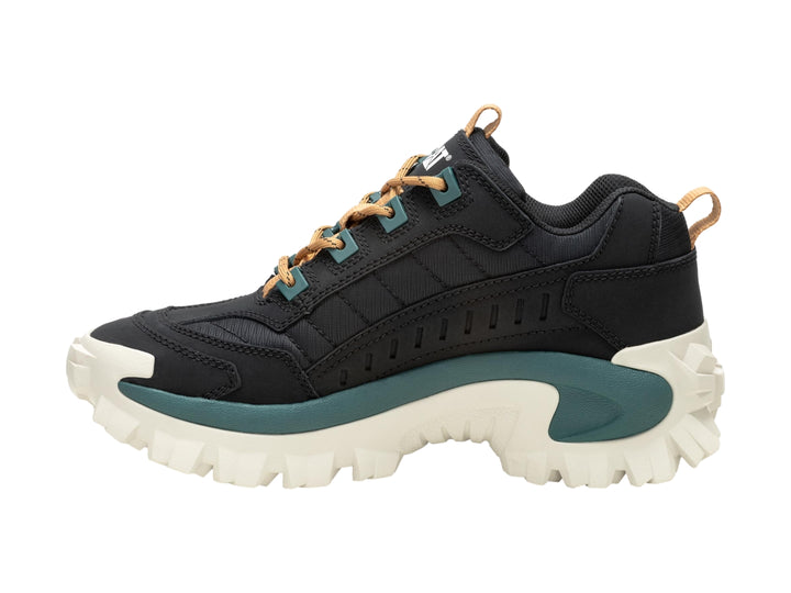 Tenis Caterpillar negros con suela gruesa color crema y detalles en verde oscuro.