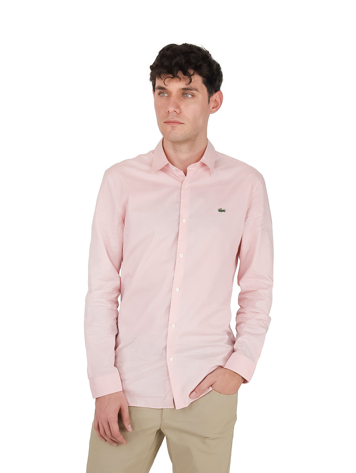 Hombre vistiendo una camisa de manga larga color rosa pálido de la marca Lacoste.