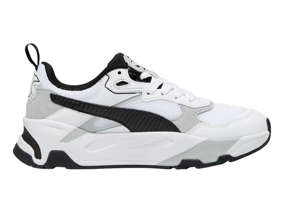 Tenis PUMA Trinity blancos con detalles en negro y gris y suela robusta.