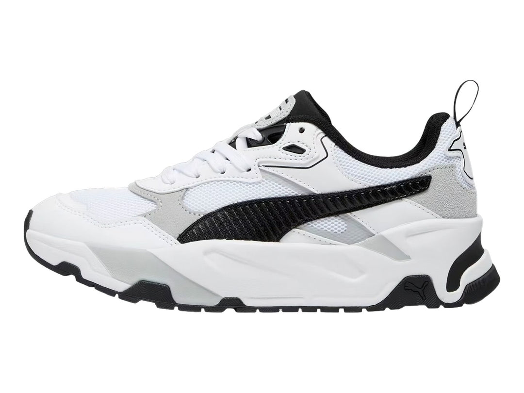 Tenis PUMA Trinity blancos con detalles en negro y gris y suela robusta.