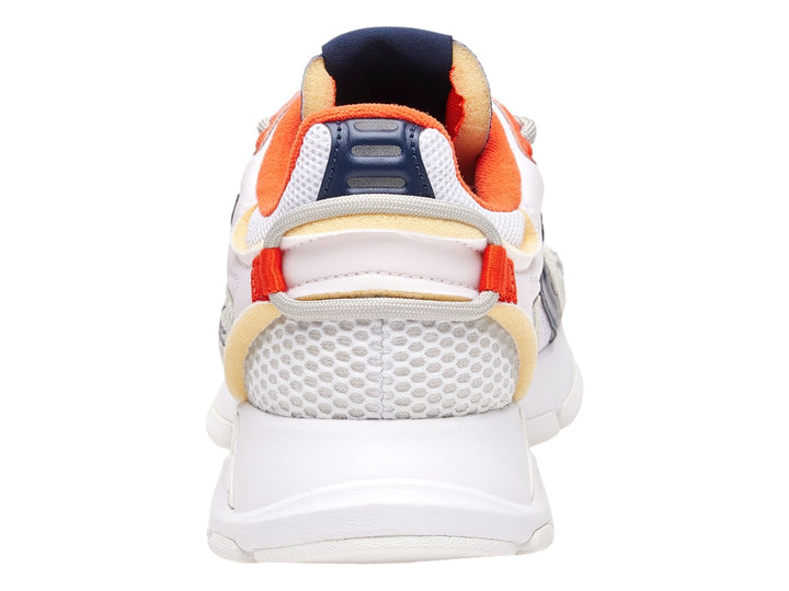 Tenis deportivos Lacoste blancos con detalles en azul marino y naranja y suela blanca gruesa.