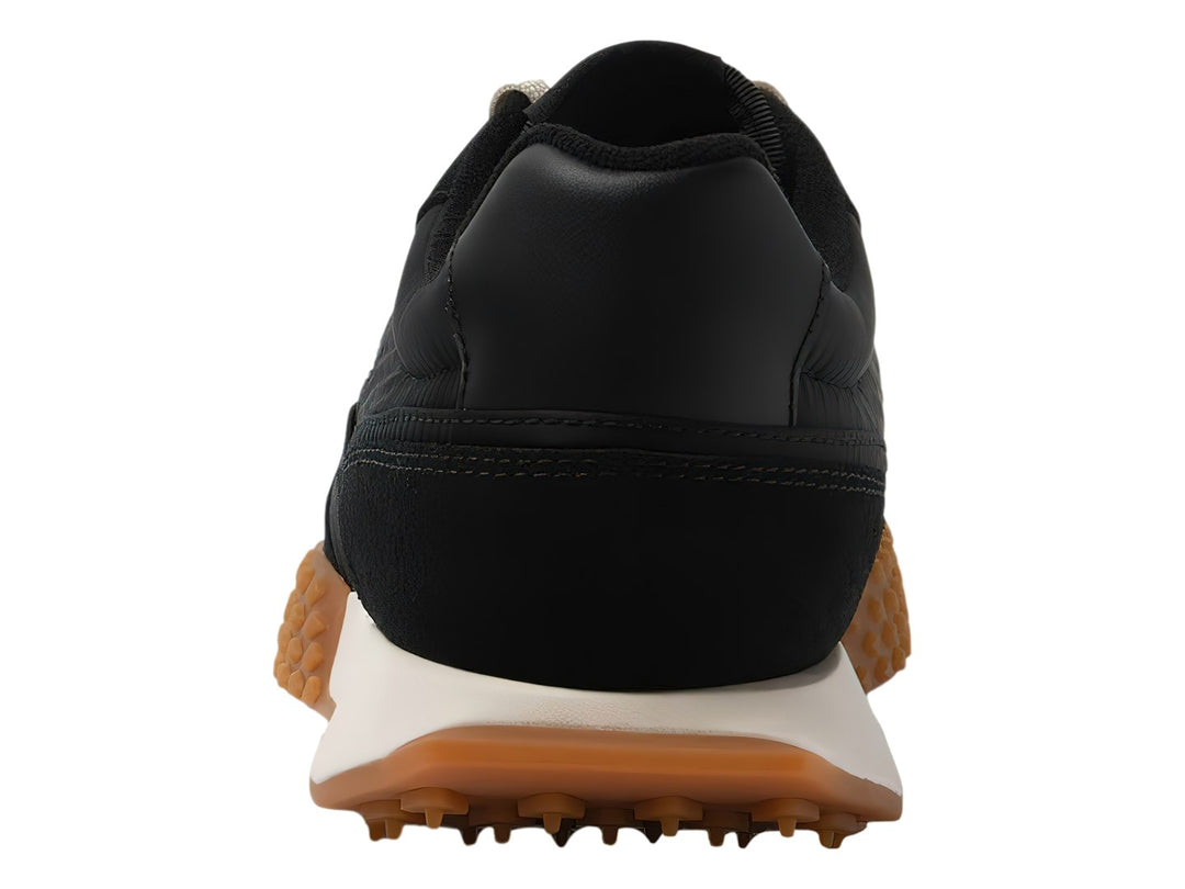 Tenis Lacoste negros con suela marrón dentada y entresuela blanca.