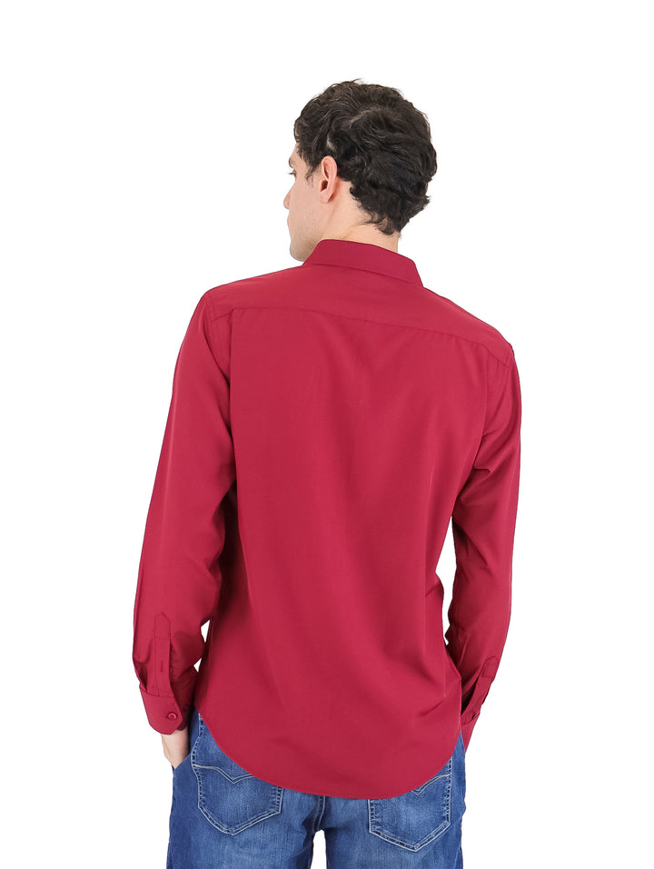 Hombre vistiendo una camisa de manga larga color borgoña y pantalones azules.