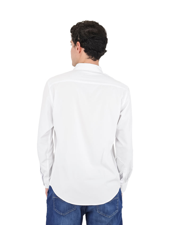 Hombre vistiendo una camisa blanca de manga larga y pantalones vaqueros azules.