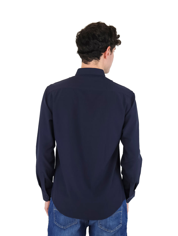 Hombre usando una camisa de manga larga color azul marino y pantalones de mezclilla.