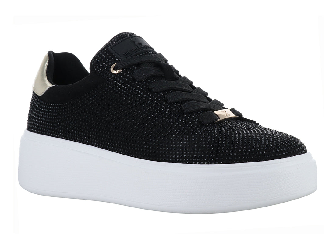 Tenis negros con detalles brillantes, suela blanca de plataforma y detalle dorado en el talón.