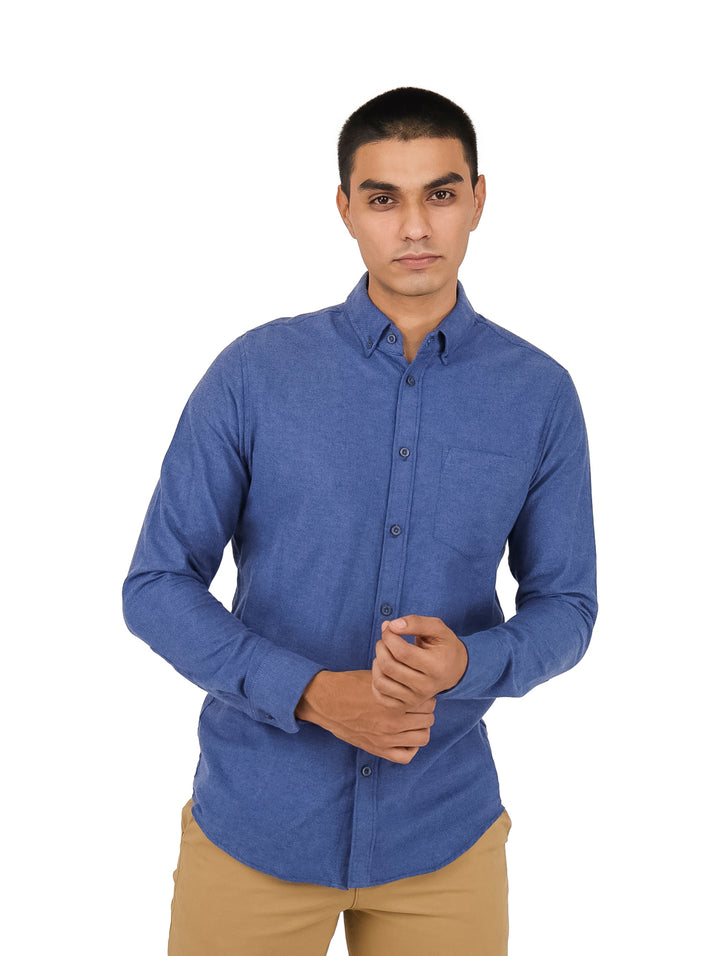 Hombre vistiendo una camisa azul de manga larga estilo mezclilla y pantalones color beige.
