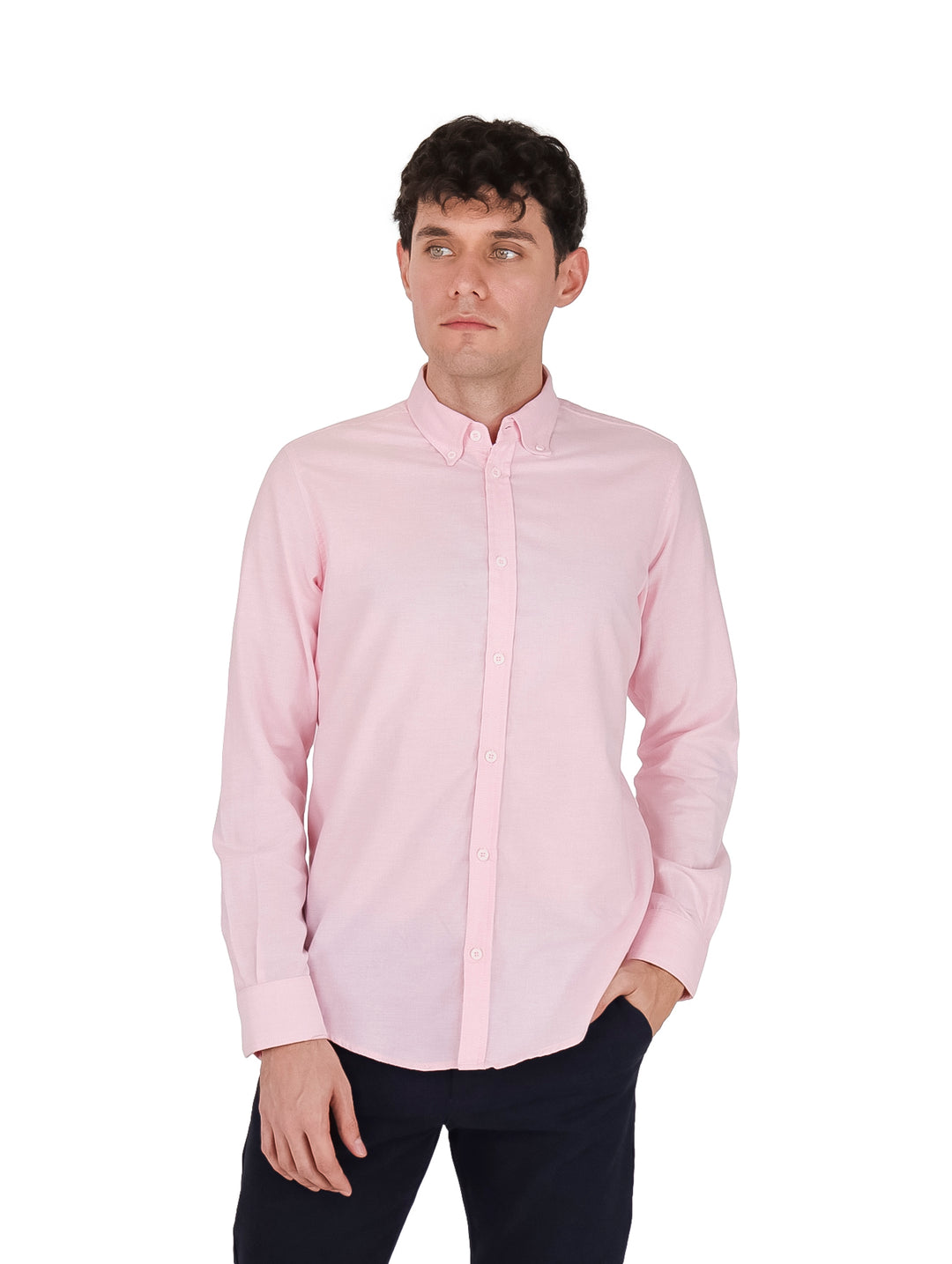Hombre vistiendo una camisa Oxford de color rosa claro con manga larga y pantalones oscuros.