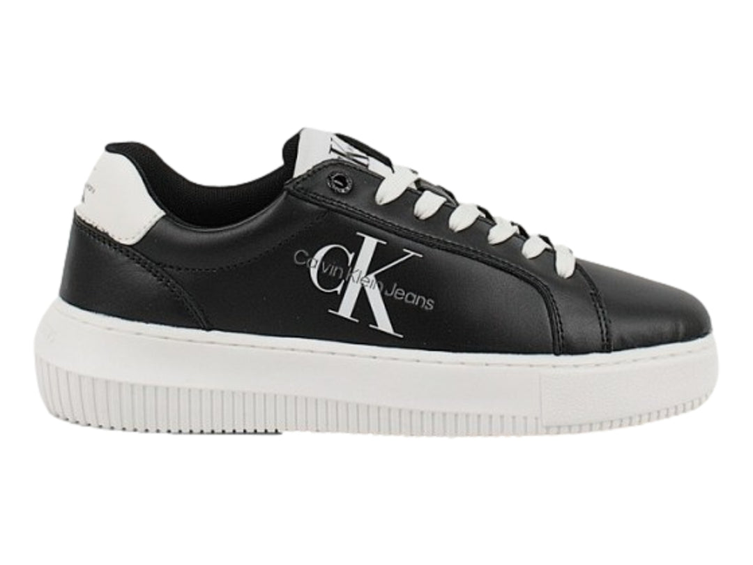 Tenis Calvin Klein negros con suela blanca gruesa y detalles en blanco en el talón.