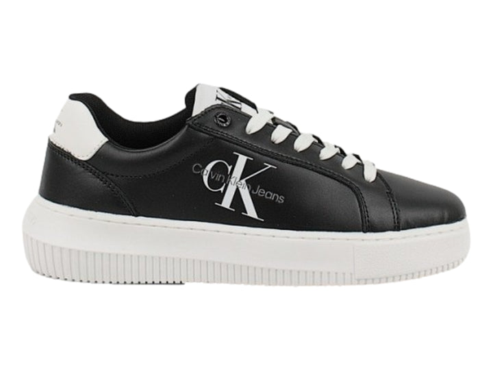 Tenis Calvin Klein negros con suela blanca gruesa y detalles en blanco en el talón.