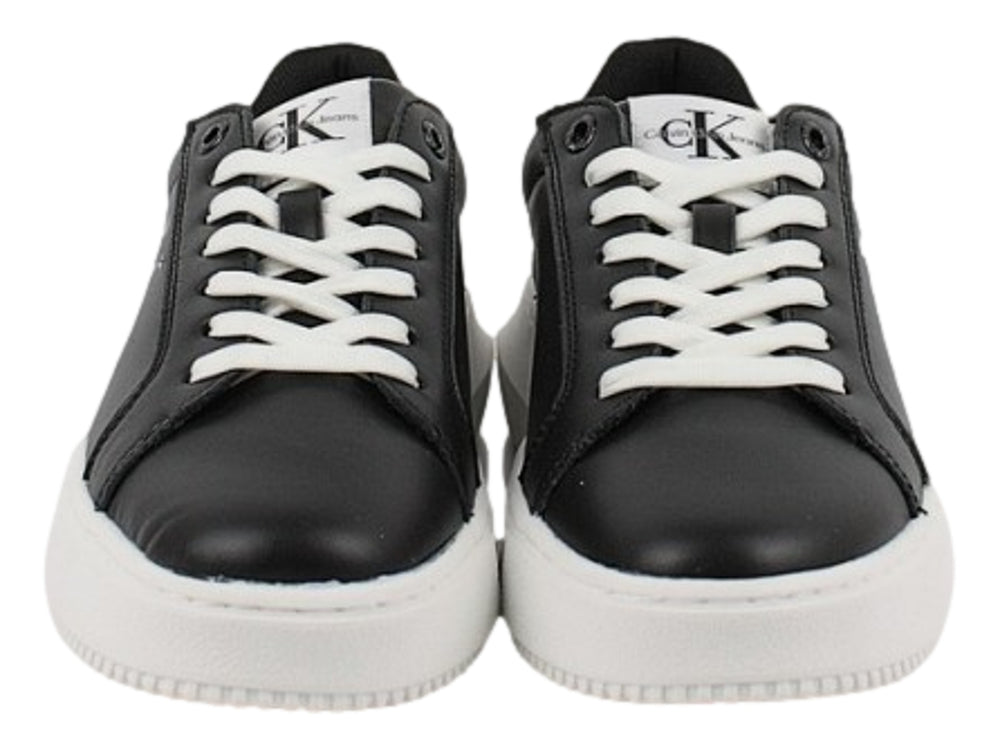 Tenis Calvin Klein negros con suela blanca gruesa y detalles en blanco en el talón.