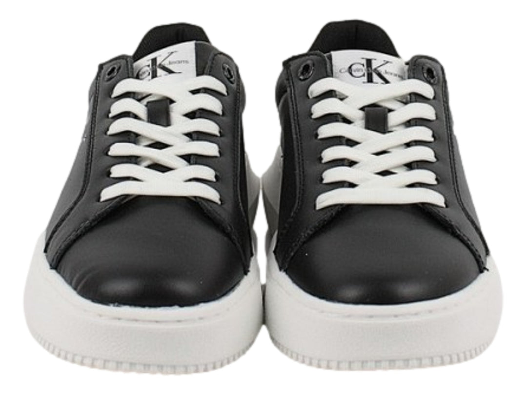 Tenis Calvin Klein negros con suela blanca gruesa y detalles en blanco en el talón.