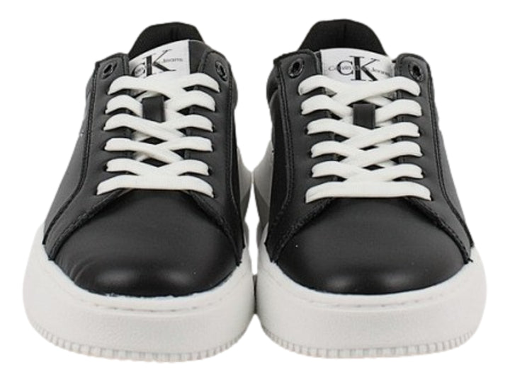 Tenis Calvin Klein negros con suela blanca gruesa y detalles en blanco en el talón.