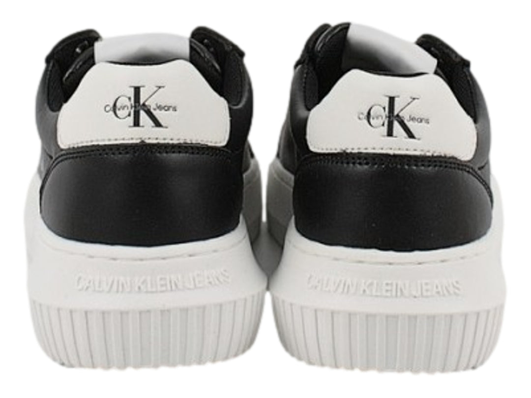 Tenis Calvin Klein negros con suela blanca gruesa y detalles en blanco en el talón.