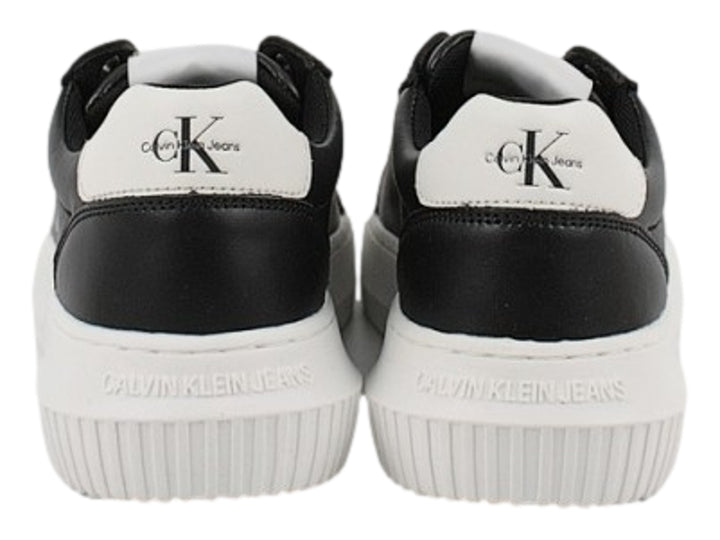 Tenis Calvin Klein negros con suela blanca gruesa y detalles en blanco en el talón.