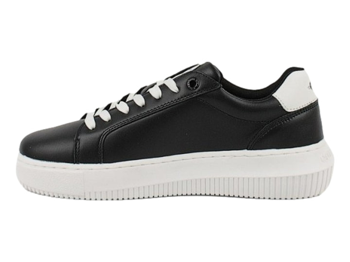 Tenis Calvin Klein negros con suela blanca gruesa y detalles en blanco en el talón.