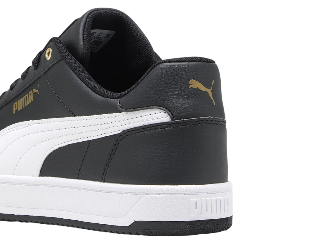 Tenis PUMA Caven 2.0 en color negro con franja lateral blanca y detalles dorados, suela blanca y negra.