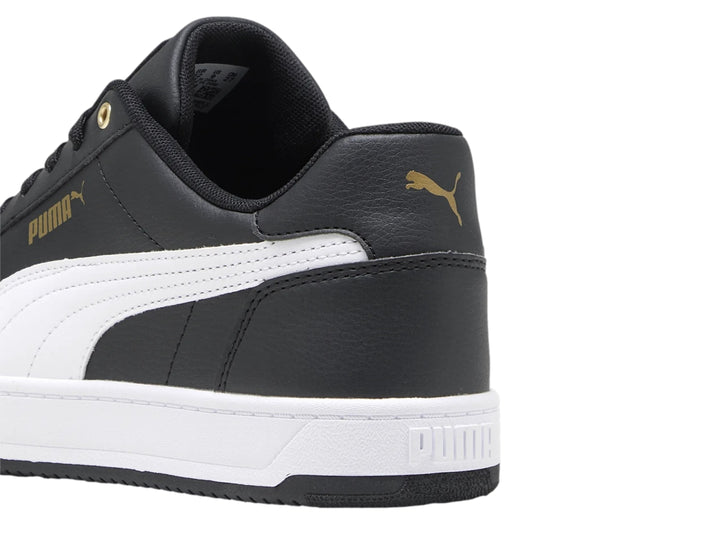 Tenis PUMA Caven 2.0 en color negro con franja lateral blanca y detalles dorados, suela blanca y negra.