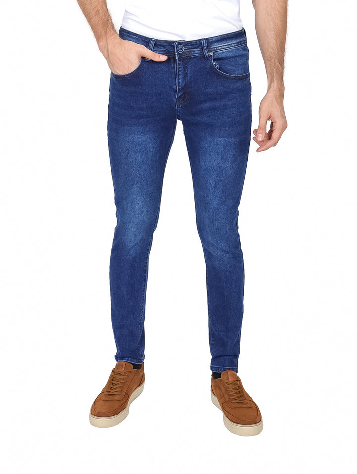 Hombre vistiendo pantalones jeans color azul con efecto de lavado stone wash y corte ajustado.