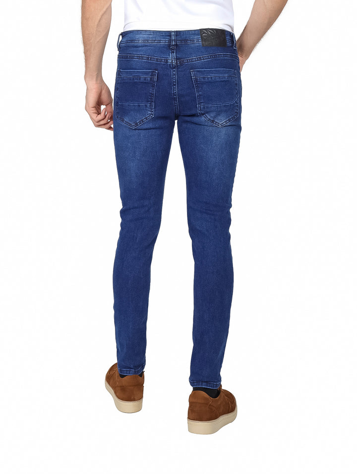 Hombre vistiendo pantalones jeans color azul con efecto de lavado stone wash y corte ajustado.
