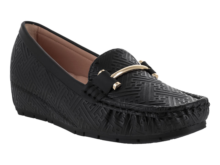 Zapato tipo mocasín color negro con textura grabada y detalle metálico dorado en la parte superior.
