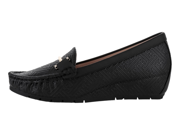 Zapato tipo mocasín color negro con textura grabada y detalle metálico dorado en la parte superior.