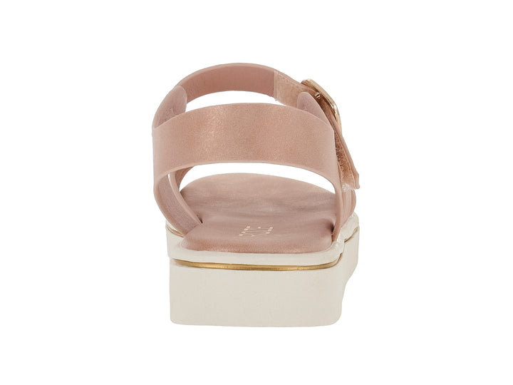 Sandalia color nude para niña con tiras cruzadas, hebilla ajustable y suela blanca de plataforma dentada.