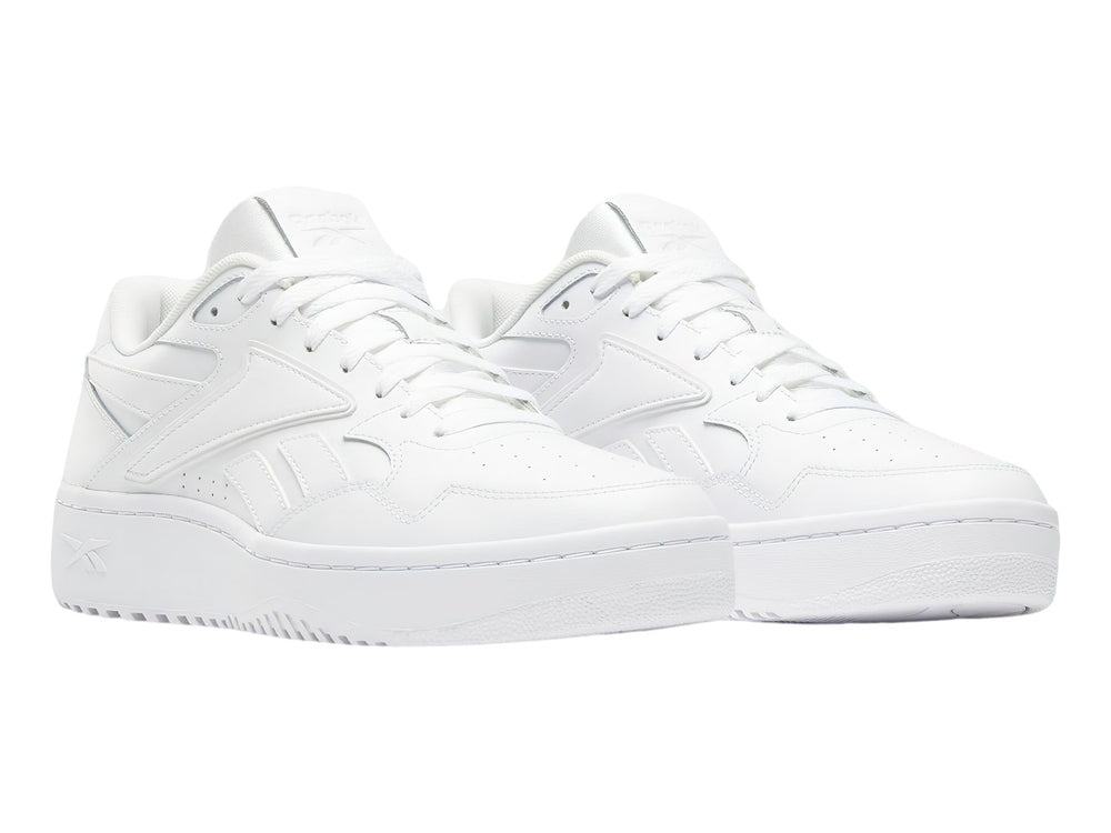 Tenis blancos Reebok de corte bajo con suela plana y cordones.