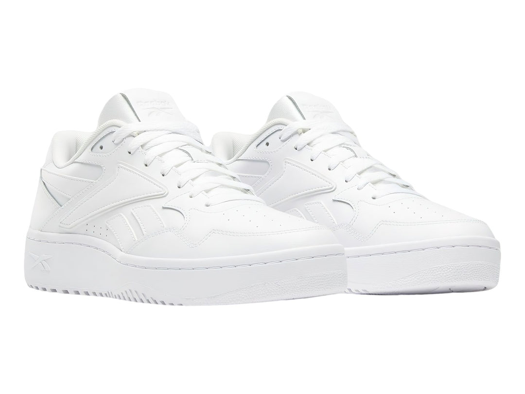 Tenis blancos Reebok de corte bajo con suela plana y cordones.