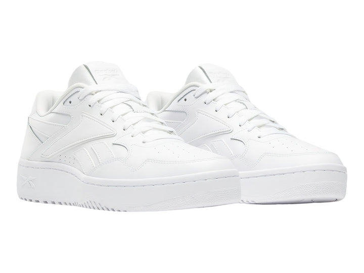 Tenis blancos Reebok de corte bajo con suela plana y cordones.