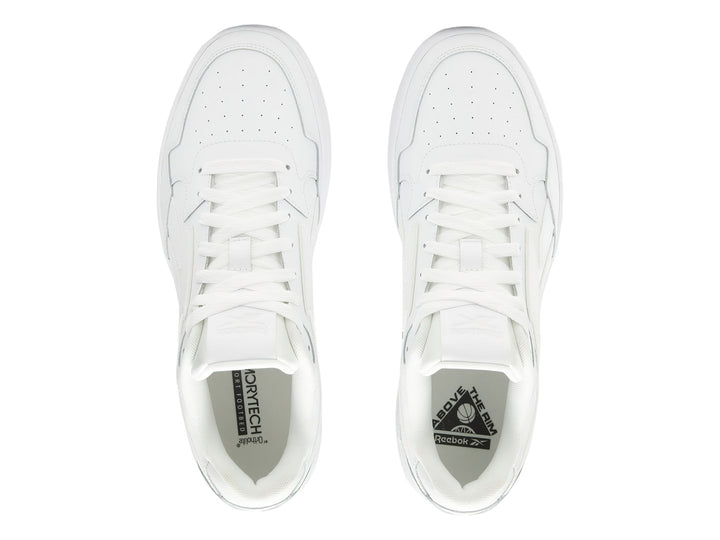 Tenis blancos Reebok de corte bajo con suela plana y cordones.