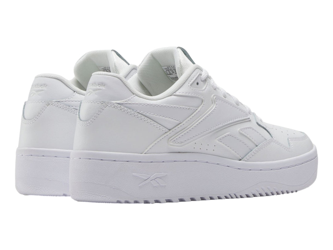 Tenis deportivos Reebok color blanco para niños, con suela ancha y diseño clásico de cuero sintético.