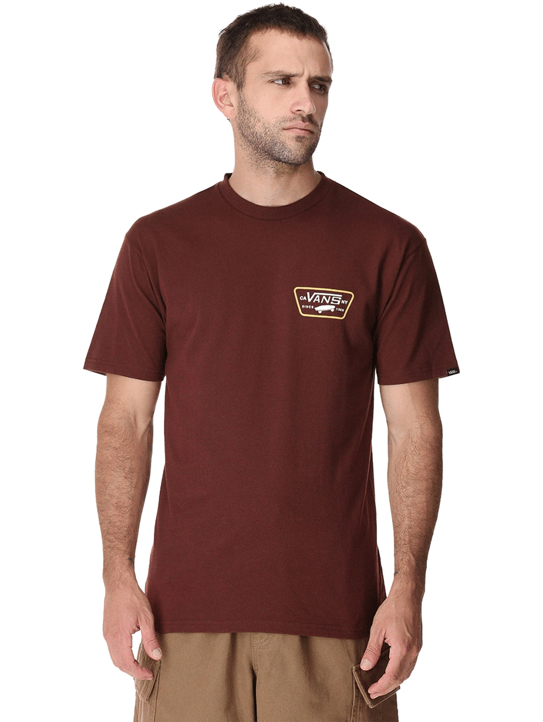 Hombre vistiendo una camiseta de manga corta color marrón chocolate con un parche frontal de la marca Vans.