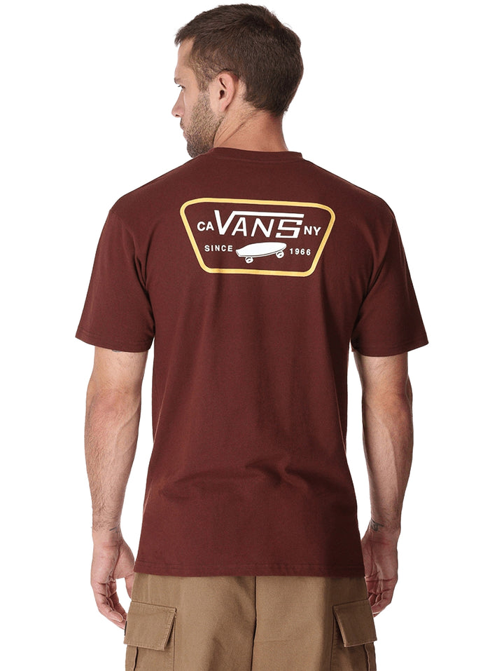 Hombre vistiendo una camiseta de manga corta color marrón chocolate con un parche frontal de la marca Vans.
