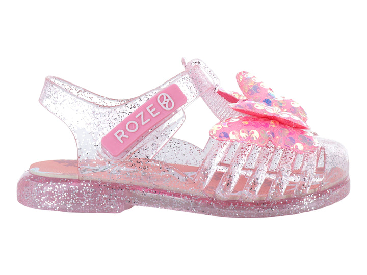 Sandalias infantiles color rosa con glitter, material transparente y un moño decorativo en la parte superior.