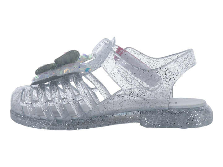 Sandalia infantil color plata con glitter y un moño iridiscente en la parte frontal.