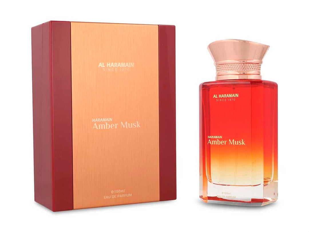 Perfume Al Haramain Amber Musk de 100ml en botella de vidrio con degradado rojo y dorado junto a su caja.