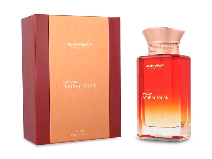 Perfume Al Haramain Amber Musk de 100ml en botella de vidrio con degradado rojo y dorado junto a su caja.