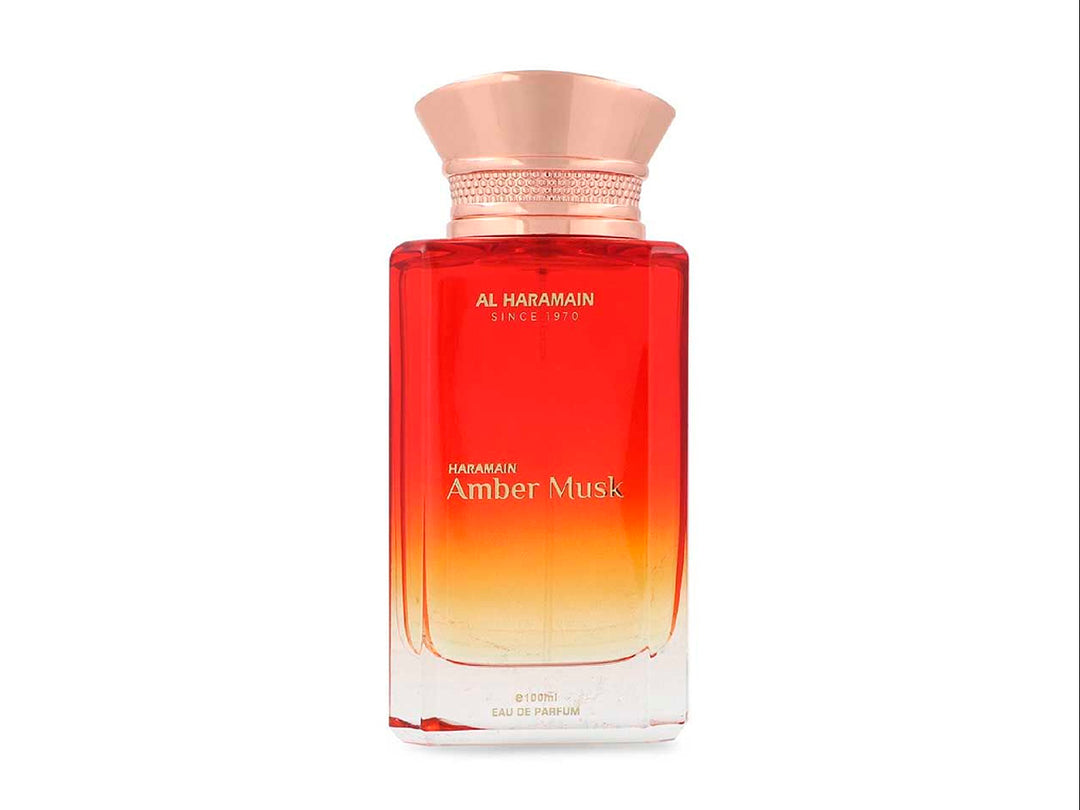 Perfume Al Haramain Amber Musk de 100ml en botella de vidrio con degradado rojo y dorado junto a su caja.