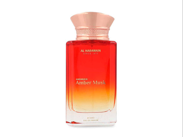 Perfume Al Haramain Amber Musk de 100ml en botella de vidrio con degradado rojo y dorado junto a su caja.