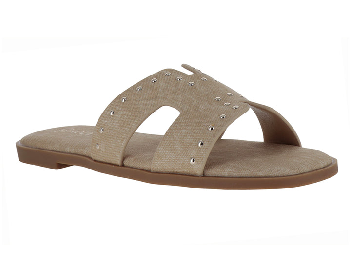 Sandalias planas color beige para mujer con detalles de remaches metálicos en la banda superior.