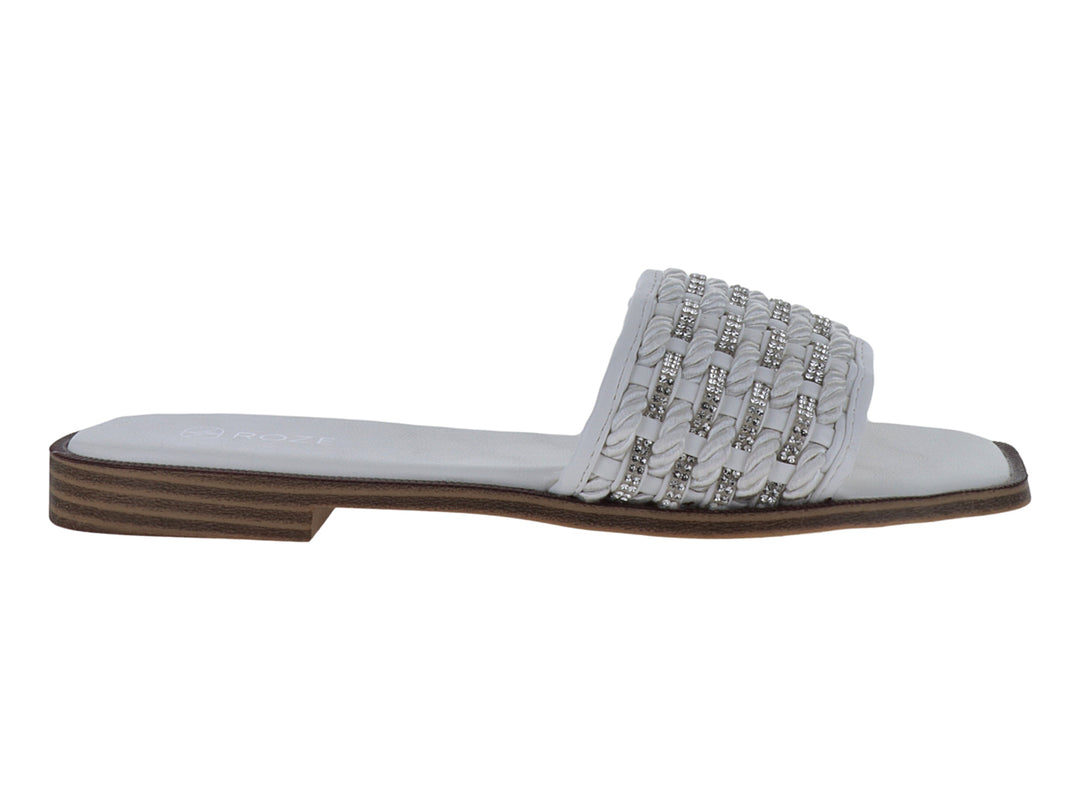 Sandalia blanca con tira trenzada y detalles brillantes, suela café con rayas horizontales.